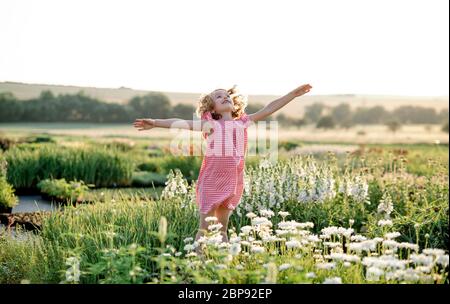 Cheerful small girl running in the backyard garden, having fun. Stock Photo