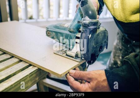 Master cuts the tile using an angle grinder with special diamond disc. Angle grinder in operation, close-up view Stock Photo