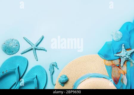Summer fashion on blue and coral background. Blue flip flops, seashells, and straw hat. Flat lay, top view with copy space. Stock Photo