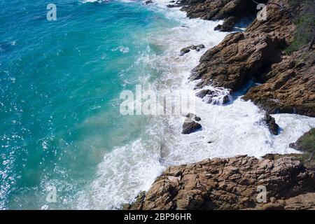 Aerial drone view of ocean's beautiful waves crashing on the rocky island coast Stock Photo