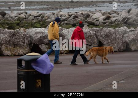 Morecambe, Lancashire, United Kingdom. 18th May, 2020. The weather turns with dog walks battling high winds and rain blowing down the promenade Credit: PN News/Alamy Live News Stock Photo