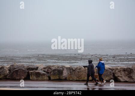 Morecambe, Lancashire, United Kingdom. 18th May, 2020. The weather turns with dog walks battling high winds and rain blowing down the promenade Credit: PN News/Alamy Live News Stock Photo