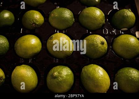 A close-up shot of an abundance of fresh Green Limes on display at a market stall. Stock Photo