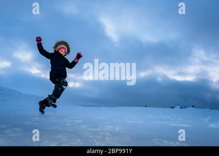 Happy little girl jumping in the snow among the wonderful winter scenery in Norway Stock Photo