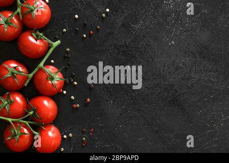 Fresh tomatoes on a black background with spices. Top view Stock Photo