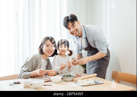 Mom and Dad and daughter at home dumplings Stock Photo