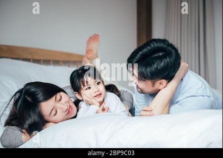 Mom and Dad and daughter in the bedroom playing games Stock Photo