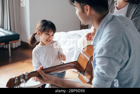 Mom and Dad and daughter sing at home Stock Photo