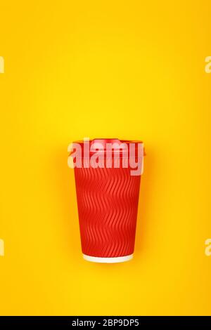 Close up one crimped disposable red paper takeaway coffee cup over vivid yellow background, flat lay, elevated top view, directly above Stock Photo