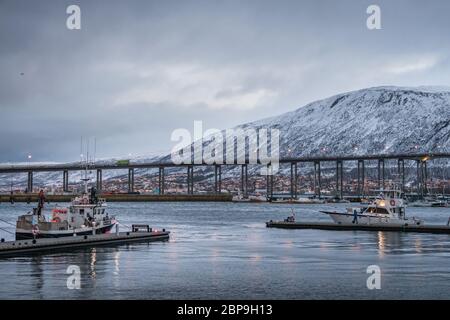 Tromso, Norway -  December 2018 : Port and harbour with famous Tromso Bridge across Tromsoysundet strait in the background Stock Photo