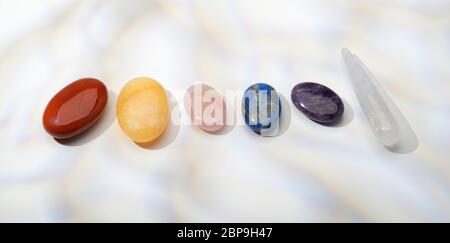 Semi precious stones in a row. Garnet, Carnelian, Rose Quartz, Lapis Lazuli, Amethyst and quartz. Chakras. Stock Photo
