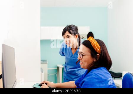 Two nurses using a computer in a x-ray room Stock Photo