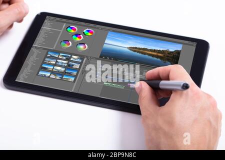 Young male editor editing video on tablet at workplace Stock Photo