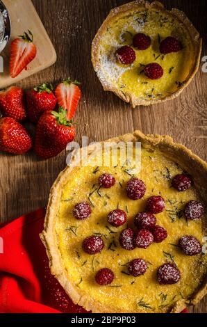 Lemon tart with rosemary and berries, filled with cream topped berries Stock Photo