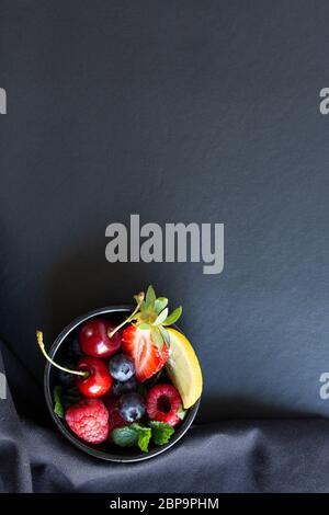 Summer fruits, berries and mint in chalk painted glass of juice on black background. Conceptual healthy, vitamin, diettary food. Vegan, vegetarian and detox food and drinks. Menu mock up, poster concept Stock Photo