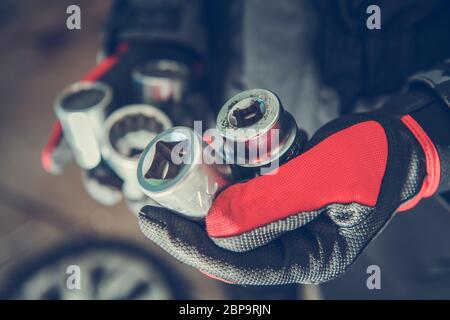 Close Up Of Person In Gloves Holding Five Lug Nut And Bolt Extractor Removal Tools. Stock Photo