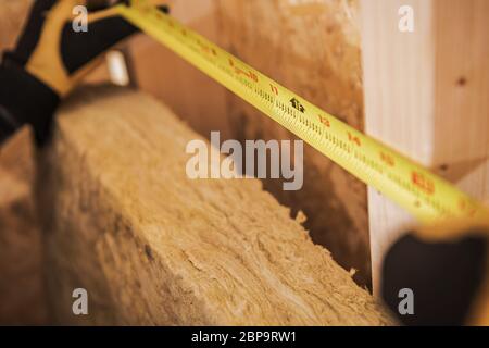 Close Up Of Carpenter Using Tape Measure To Figure Out  Distance Between Studs At New Construction Site. Stock Photo