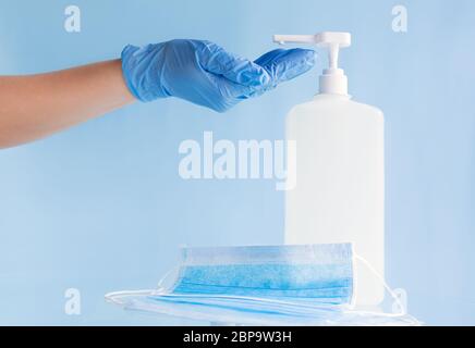 Medical face masks, surgical protective disposable mask, bottle alcohol gel. Doctor hands in gloves use sanitizer gel hand hygiene concept on blue Stock Photo
