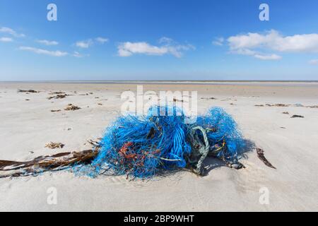 Fishing nylon net on the sand. Garbage on the beach. Dirty sea