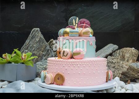 Colourful Fresh Macaroons on pastel cake in many levels on natural wooden background. Sweets concept. Stock Photo