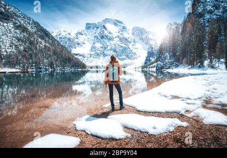 Young woman with backpack on the snowy shore of Braies lake Stock Photo