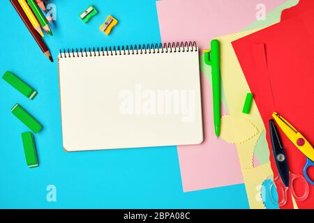 white squared  notebook, wooden colored pencils scissors on a blue background, back to school Stock Photo