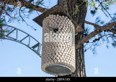 Birdhouse made from corks from wine bottles. Birdhouse on a pine tree. Stock Photo
