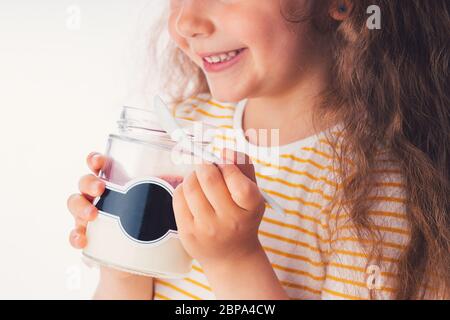 Little girl eat milky dessert with cream and fruity jelly in a jar. Stock Photo