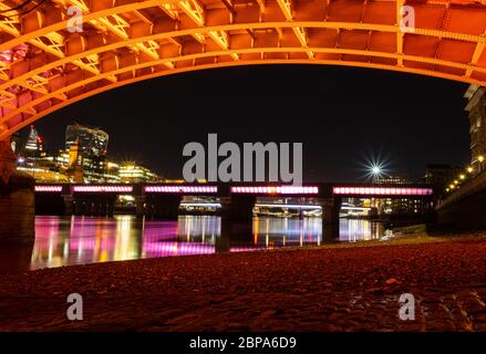 Southwark Bridge at night from below showing new illumination, ancient paving and Cannon Street Bridge in the background. Stock Photo