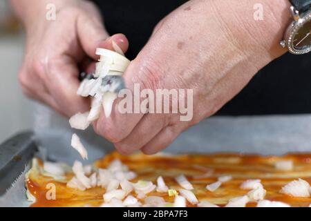 Traditional pizza cooking by italian chef at home. Adding some onion. adding ingredients on top Stock Photo