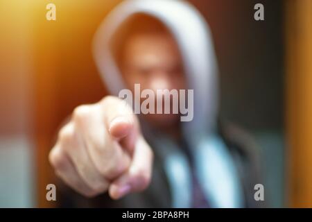 Anonymous and faceless man under hoodie pointing finger at camera isolated - incognito and mysterious criminal on internet activities concept. Stock Photo