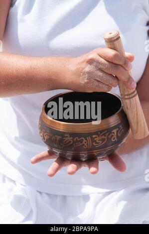 Hand holding a Cuenco, black, and white photo. The open hand of a young woman playing a Tibetan Bowls on the beach Stock Photo