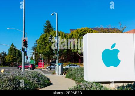 Apple logo on the sign advertising the street entrance to the campus of american multinational technology company headquarters on sunny day - Cupertin Stock Photo