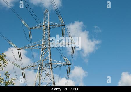 Around the UK - Electricity Pylons against a blue sky with white fluffy clouds Stock Photo