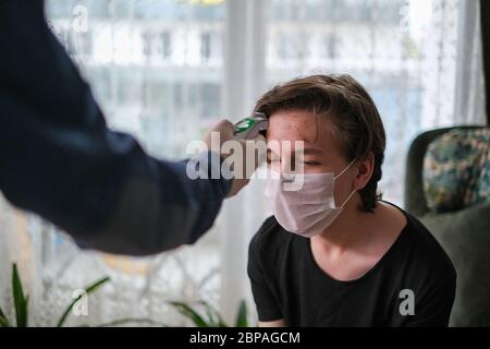 The father is checking temperature his son's with infrared thermometer at the home Stock Photo