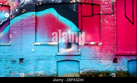 Colorfully painted wall on an abandoned building with hues of blue red black and purple Stock Photo