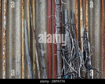 Various old sticks made from wood and metal leaning against a corrugated plastic wall Stock Photo