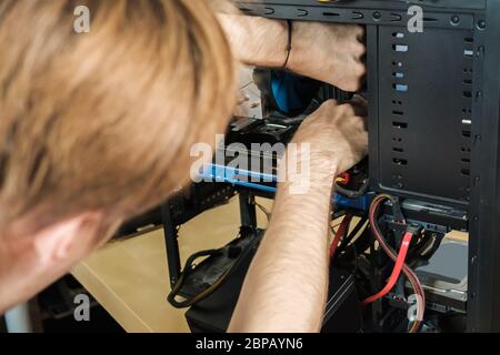 Man repairs a computer system unit, changes parts, video card and hard drive. Computer Repair Wizard Stock Photo