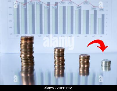 Downward red arrow icon on background of coins money and graphs. Concept of economic financial down crisis, recession. Declining trends, curve down in the world due to coronavirus pandemic Stock Photo