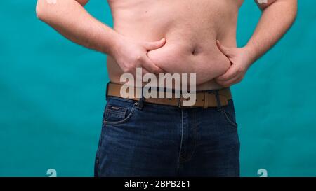 male with a big belly shows his fat on a green screen. The concept of healthy eating and losing weight, diet Stock Photo