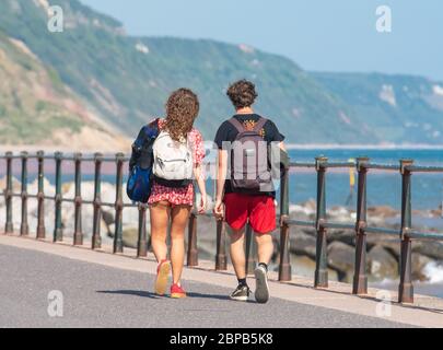 Sidmouth, East Devon, UK. 18th May, 2020. UK Weather: Families and couples enjoy a hot and sunny afternoon along the esplanade at the elegant regency town of Sidmouth. Temperatures are set to rise further this week as high pressure dominates bringing a mini-heatwave to many parts of the UK. Credit: DWR/Alamy Live News Stock Photo