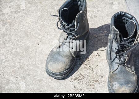 Old Black Leather army boots. Military boots of soldiers standing on the cement ground Stock Photo