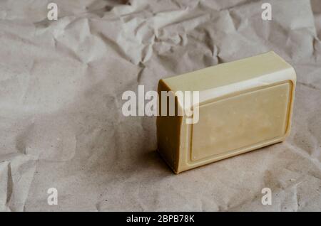 A piece of laundry soap on a plain background. A single rectangular piece of new soap. Natural hygiene products. Place for text. Selective focus. Stock Photo