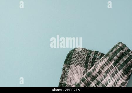 Light turquoise background with a green checkered towel. Kitchen linen towel folded casually. Minimalistic multitask background. View from above. Stock Photo