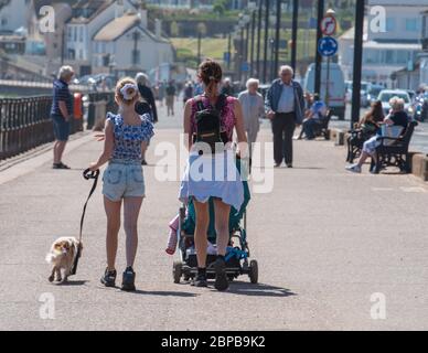 Sidmouth, East Devon, UK. 18th May, 2020. UK Weather: Families and couples enjoy a hot and sunny afternoon along the esplanade at the elegant regency town of Sidmouth. Temperatures are set to rise further this week as high pressure dominates bringing a mini-heatwave to many parts of the UK. Credit: DWR/Alamy Live News Stock Photo