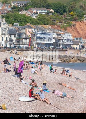 Sidmouth, East Devon, UK. 18th May, 2020. UK Weather: Families and couples enjoy a hot and sunny afternoon along the esplanade at the elegant regency town of Sidmouth. Temperatures are set to rise further this week as high pressure dominates bringing a mini-heatwave to many parts of the UK. Credit: DWR/Alamy Live News Stock Photo