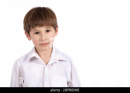 Portrait of a seven year old boy on a white background. Primary school student. Beautiful child in a white shirt . Stock Photo