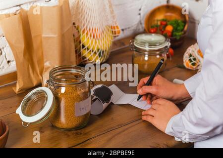 woman hand is writing name of product to stick on glass jar conscious shopping no plastic Stock Photo