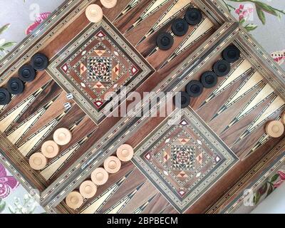 Backgammon with wooden inlay.  Wooden backgammon board game of pearl inlaid on brown background. Stock Photo