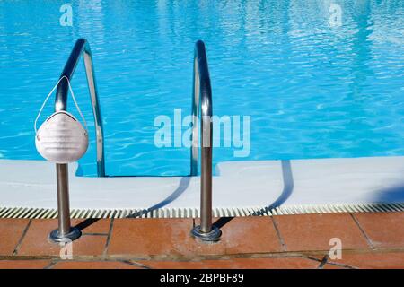 Swimming pool and medical protective mask on summer during coronavirus COVID-19 Stock Photo